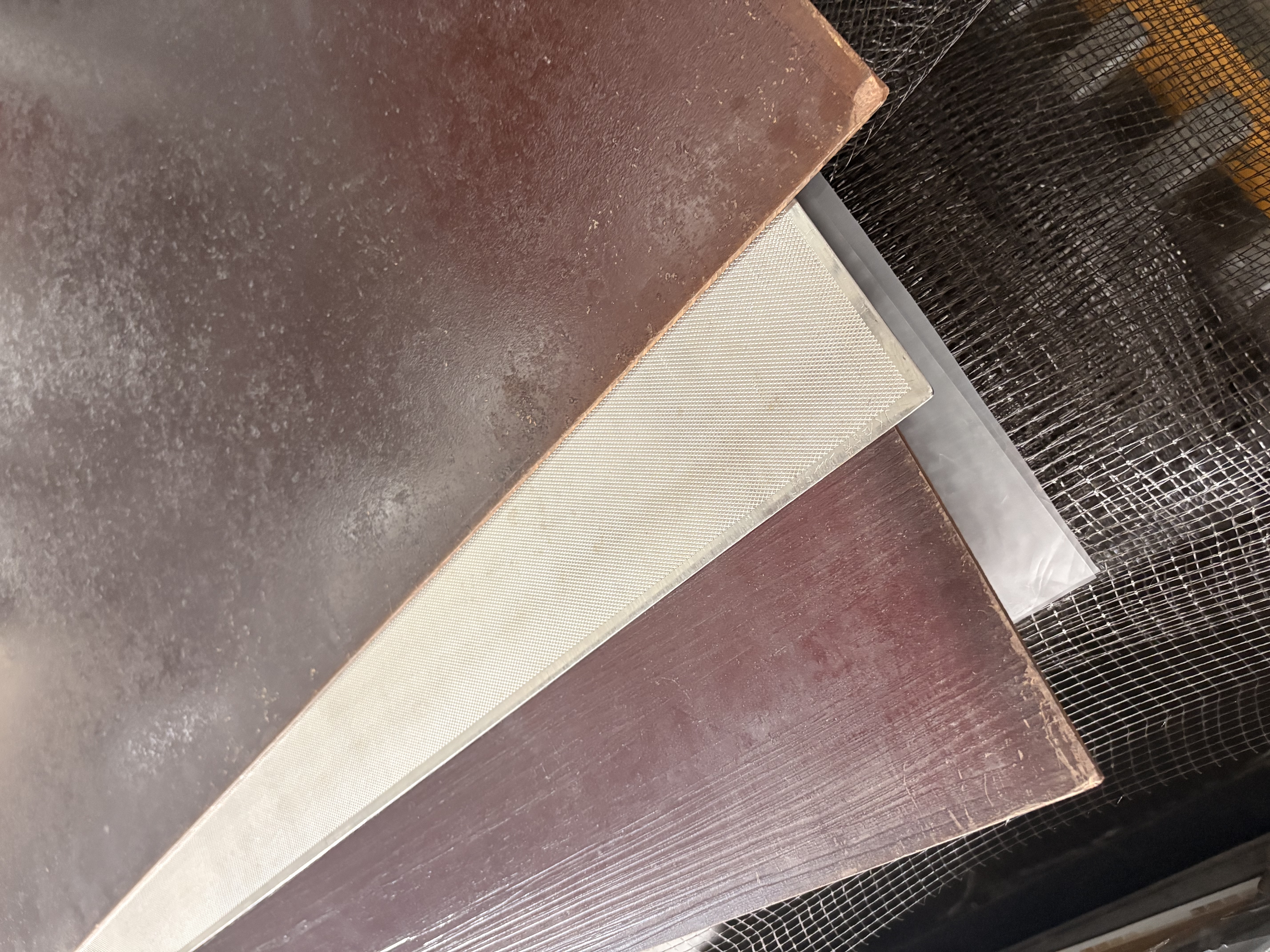 Workers at the lamination press handling large white wear-layer sheets